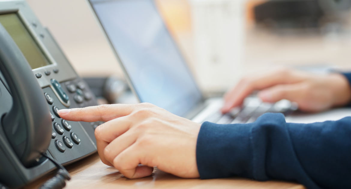 employee man hand press number on telephone for contact with someone